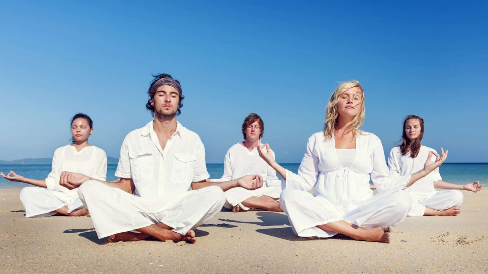 Grupo meditando sentado en una playa