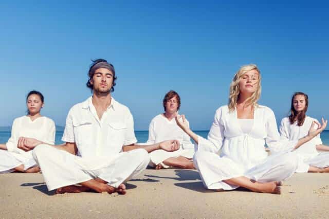 Grupo meditando sentado en una playa