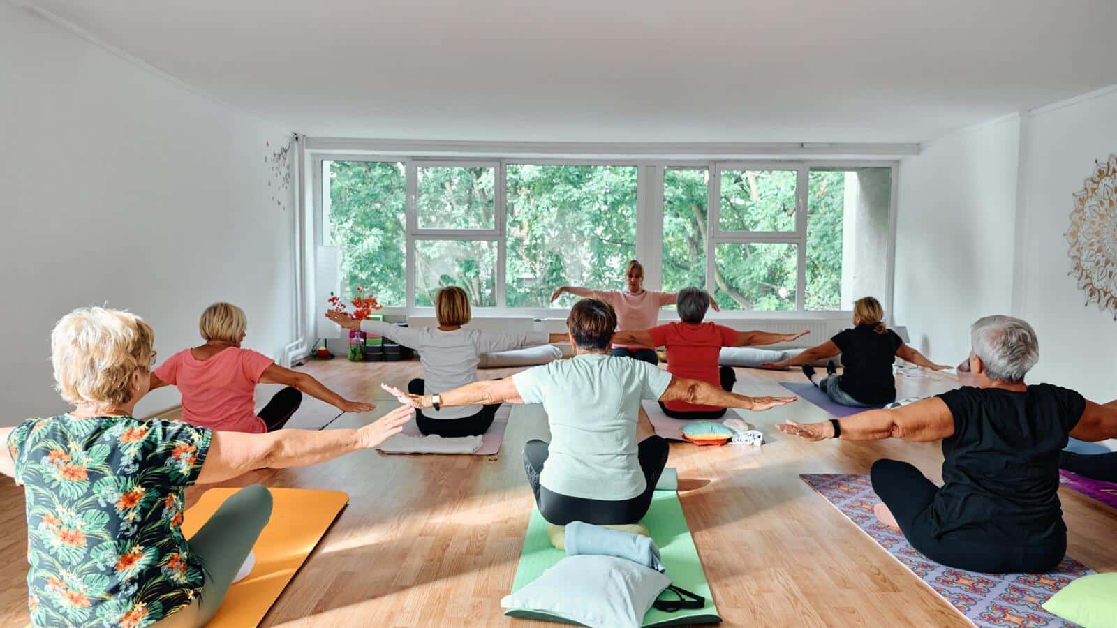 Clase de yoga en una sala luminosa con ventanales