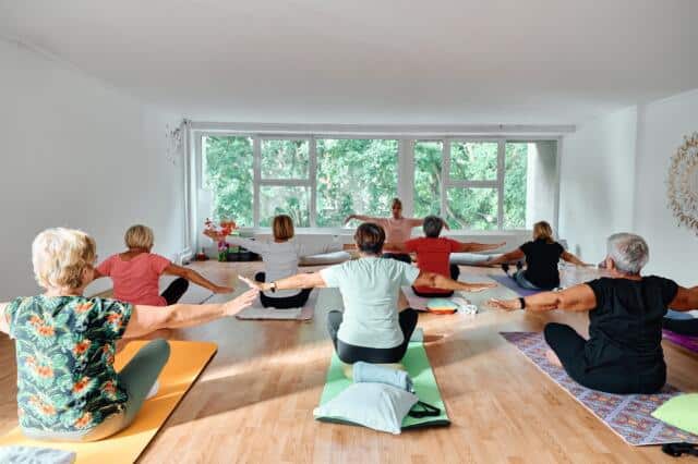 Clase de yoga en una sala luminosa con ventanales