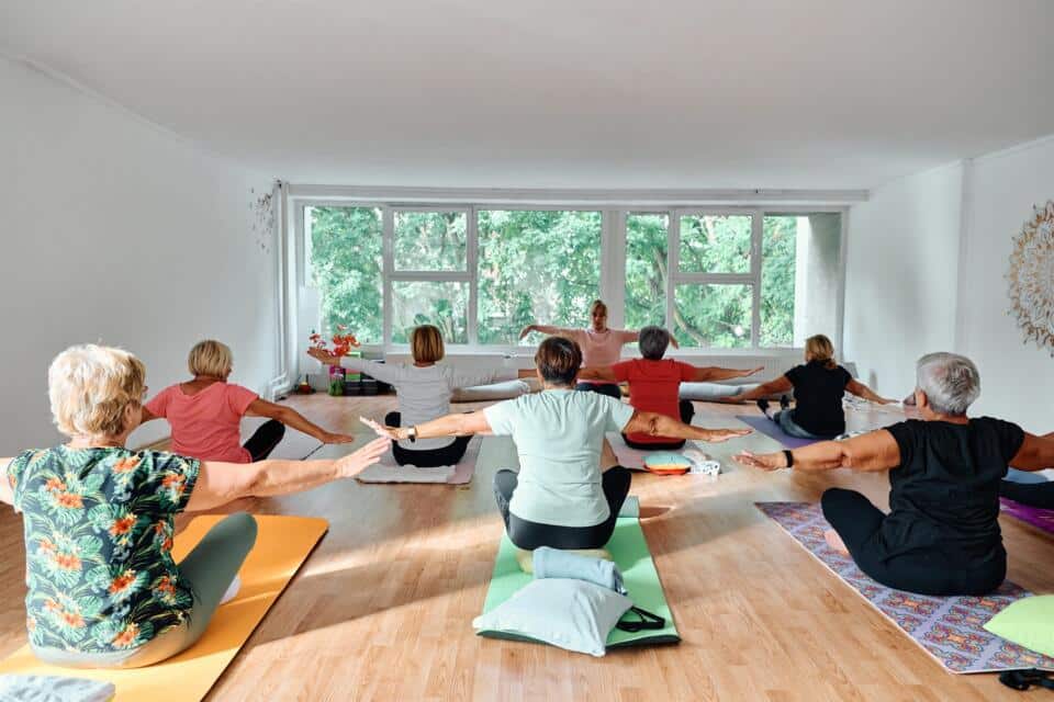 Clase de yoga en una sala luminosa con ventanales