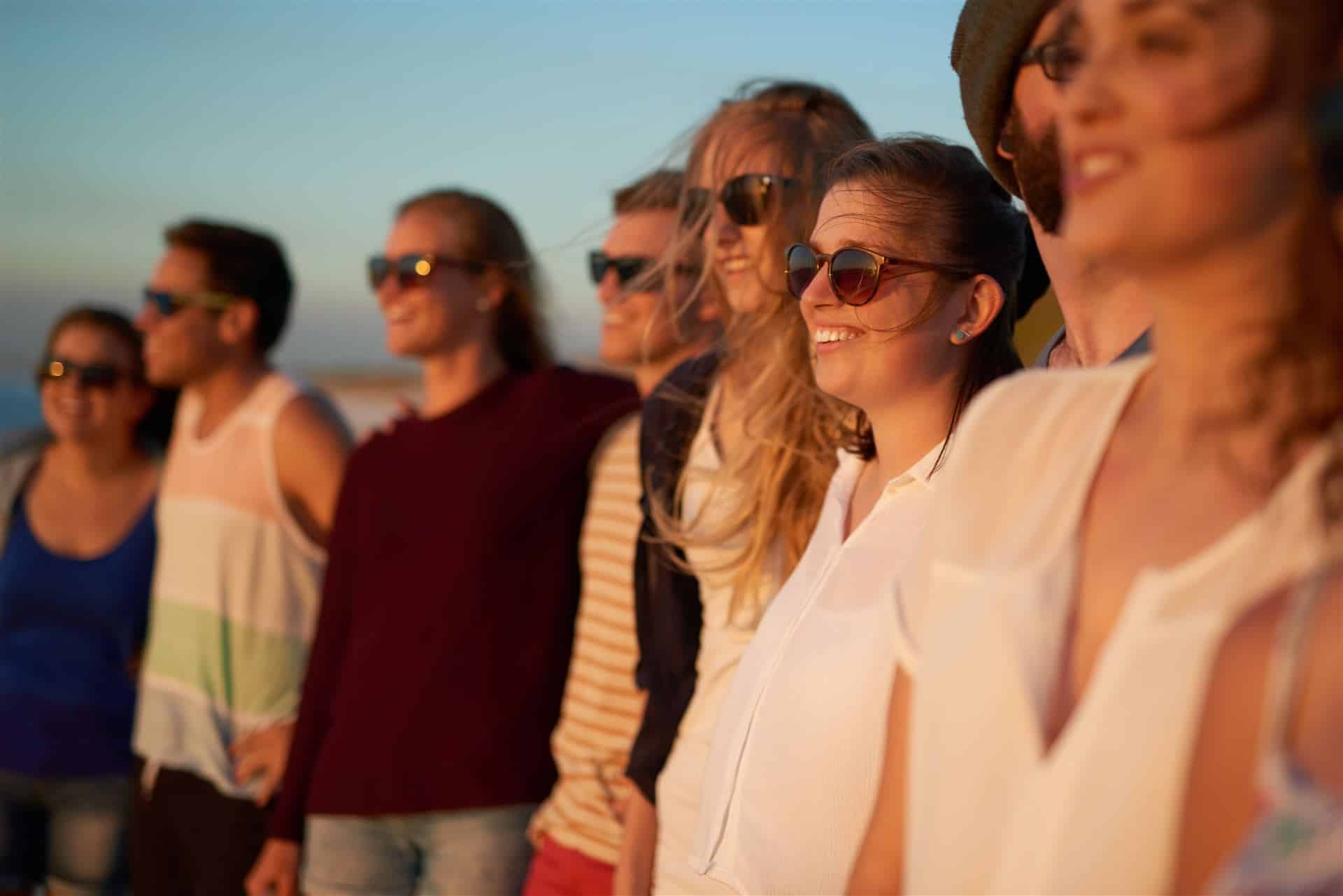 Grupo de personas viendo juntas el atardecer en la playa